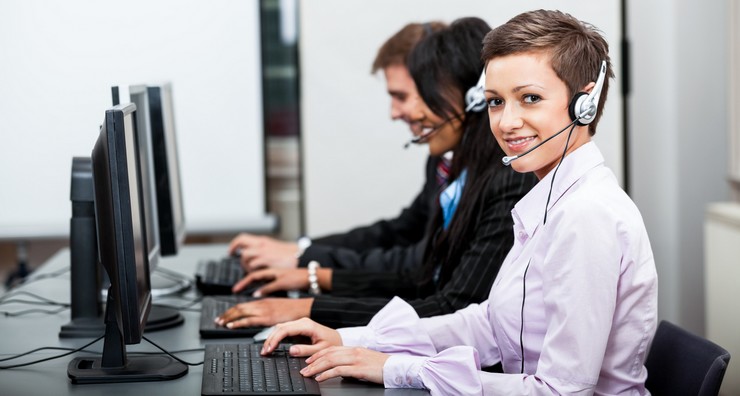 Callcenter Mitarbeiter mit Kopfhörern am Computer freundlich