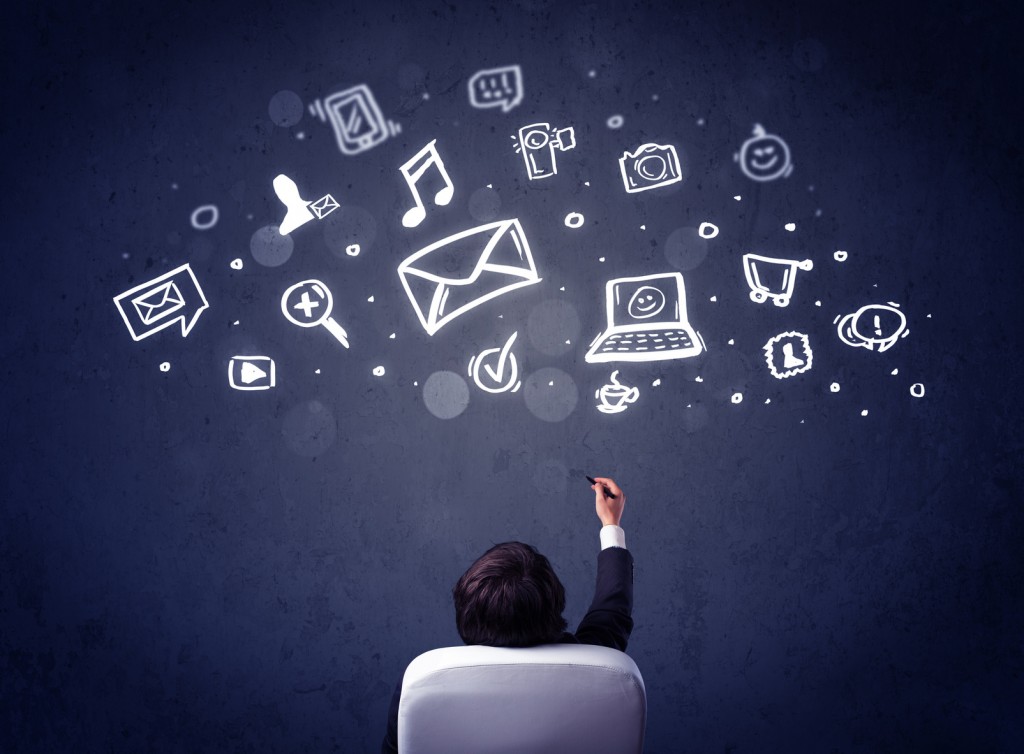 Businessman in chair with multimedia icons over his head